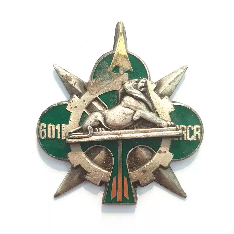 Insigne du 601e régiment de circulation routière, illustré d'un trèfle vert, d’une roue dentée, d’un lion couché...