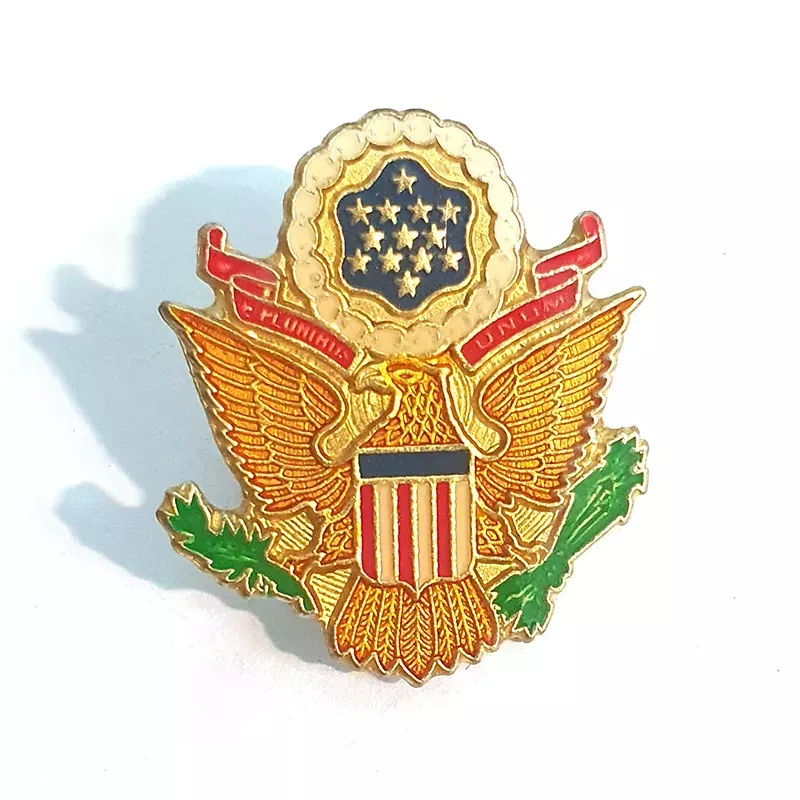 Pin's représentant un aigle doré avec un bouclier aux couleurs du drapeau des états unis, 
une bannière rouge "E pluribus unum".