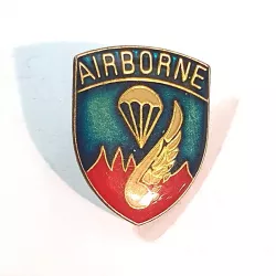 Pin's "AIRBORNE" représentant un parachute, un oiseau doré sur un bouclier aux couleurs bleu et rouge avec des bordures dorées.