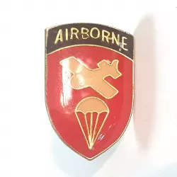 Pin's bouclier avec le titre doré "AIRBORNE" sur un fond bleu, ainsi qu'un avion et un parachute jaune sur fond rouge.