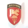 Pin's bouclier avec le titre doré "AIRBORNE" sur un fond bleu, ainsi qu'un avion et un parachute jaune sur fond rouge.