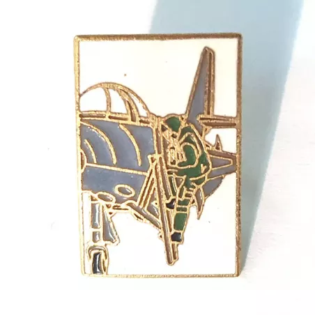 Pin's rectangulaire, orientation portrait, représentant un pilote d'avion (en vert) montant dans le cockpit d'un avion gris.