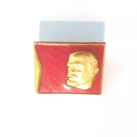 Pin's rectangulaire, orientation paysage, illustré avec la tête de Lénine couleur or et en relief sur un fond rouge.