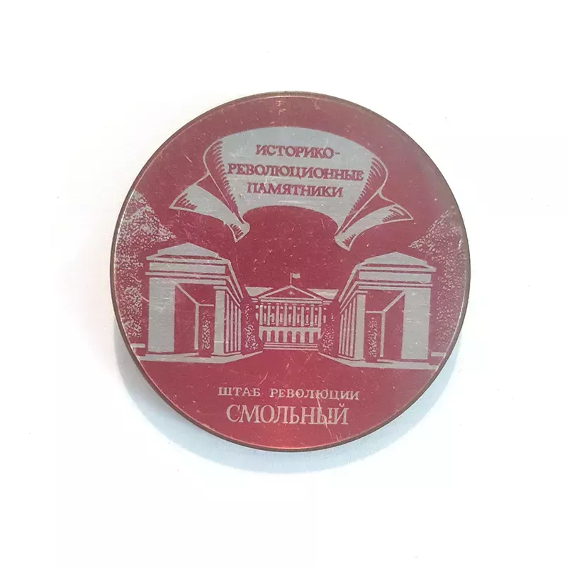 Insigne en métal, de forme ronde, avec une face rouge et blanche et un dos en or. 
Dessin de l'Institut Smolny "Смольный".