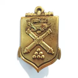 Insigne École d'Application de l'Artillerie, de couleur bronze, en forme d'écu fusionnée à une encre avec symboles en relief.