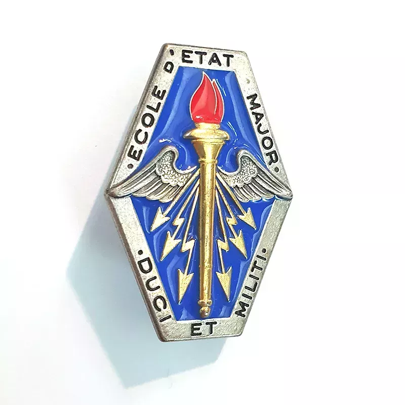 Insigne de École d'État-Major, en forme de losange, illustré par une torche aillée accompagnée de flèches.